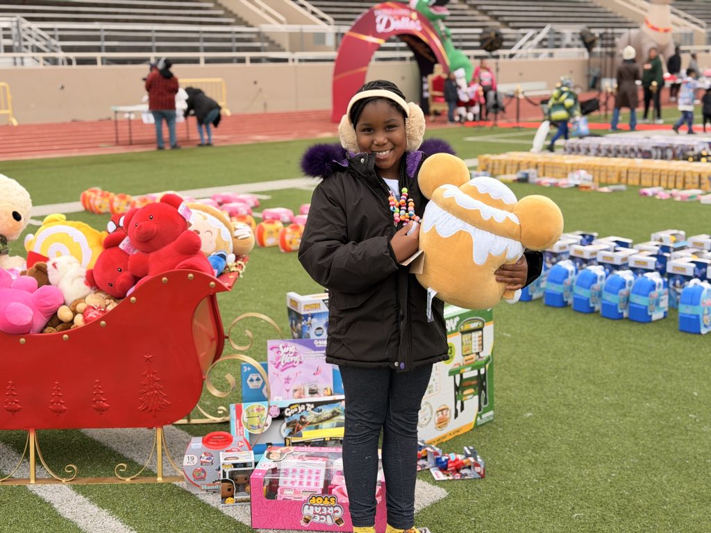 Student holding stuffed toy in front of santa sleigh