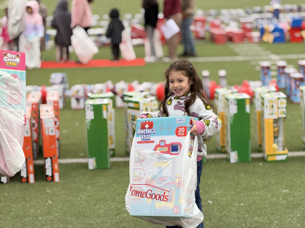 Young girl smiling with bag full of toys