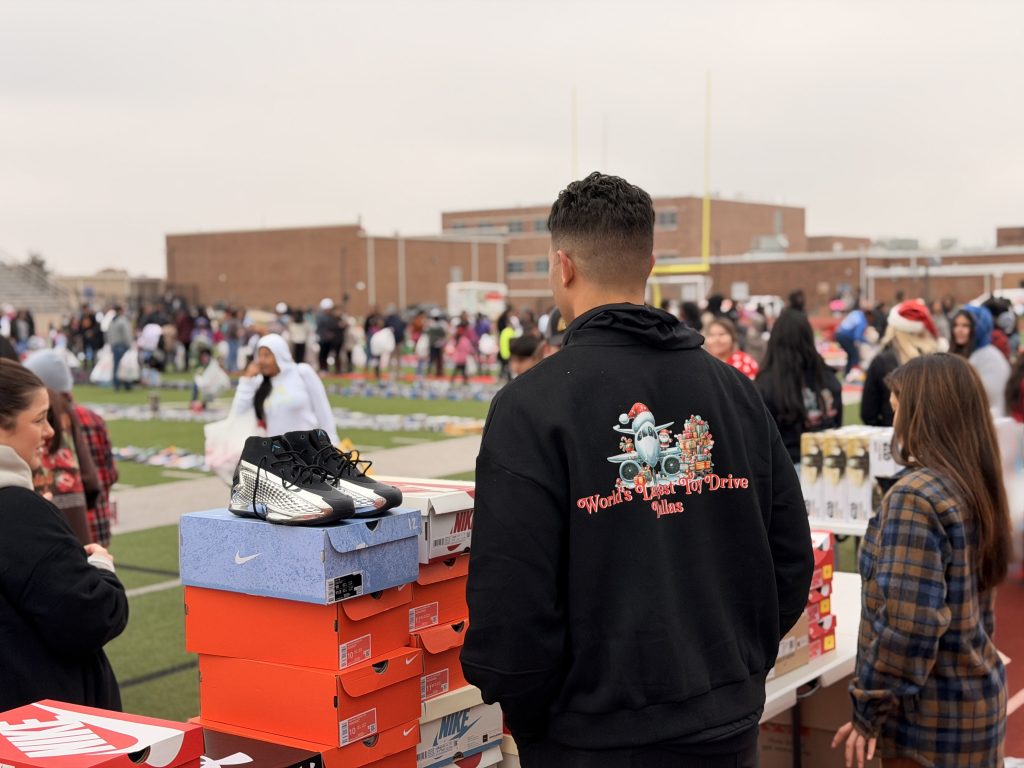 Volunteer with Worlds Largest Toy Drive jacket handing out shoes