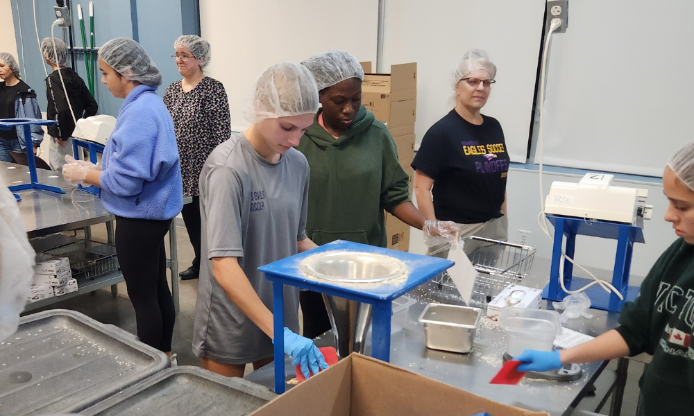 Students volunteering at a food foodbank weighing and bagging boxes for donation