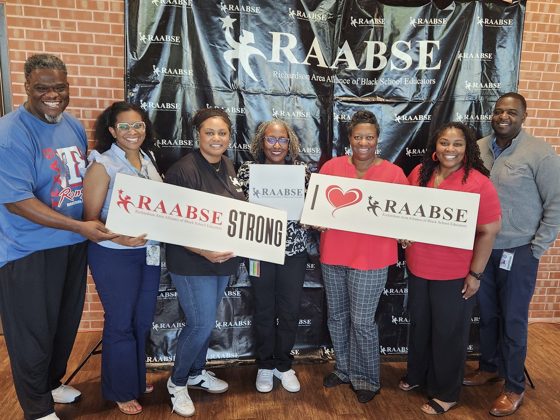 RAABSE members in front of backdrop holding signs saying "I love RAABSE"