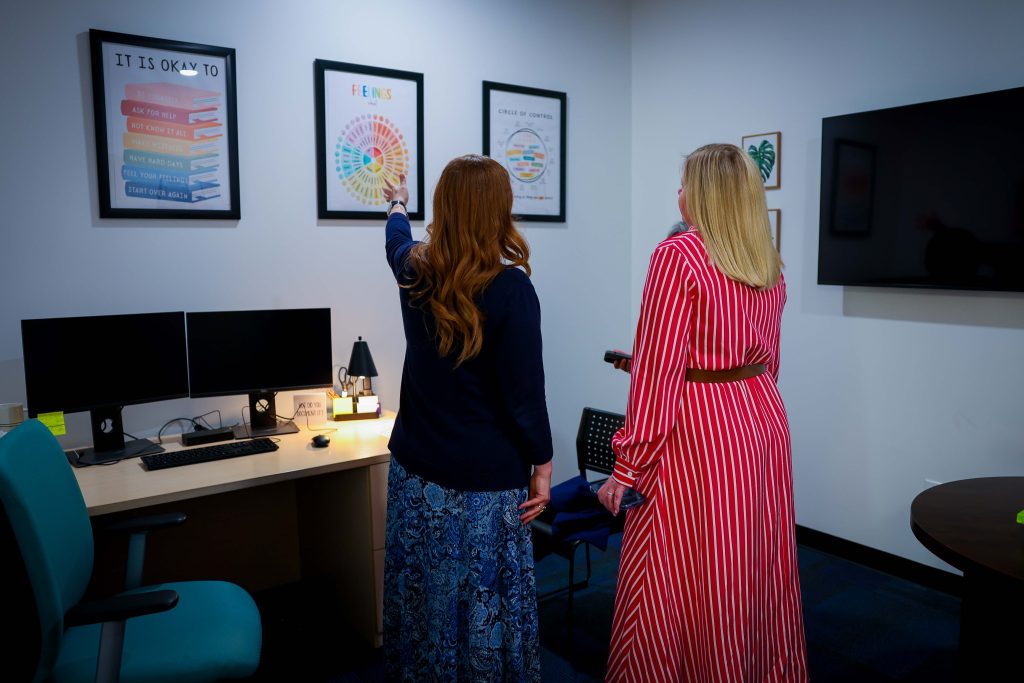 superintendent branum and dr. martin lookin at one of the clinic rooms and the mental health posters on the wall