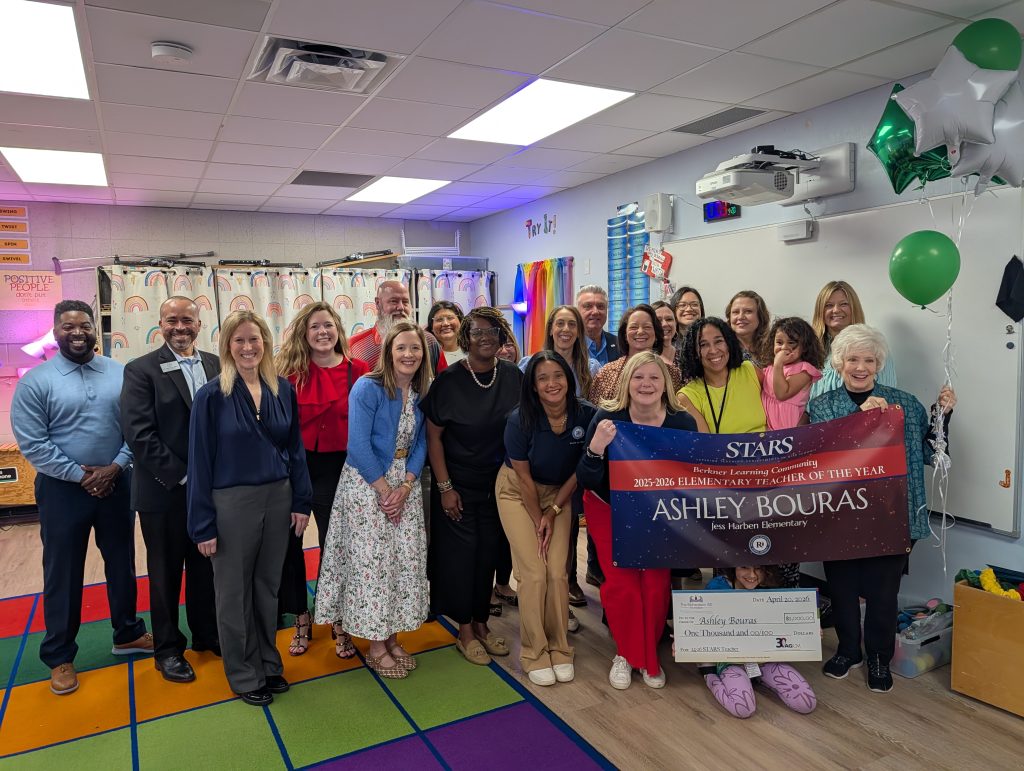 Ashley Bouras - JHE holding STARS teacher sign, big check, surrounded by prize patrol