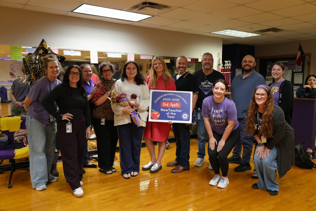 Nataly Garza holding Red Apple poster surrounded by team