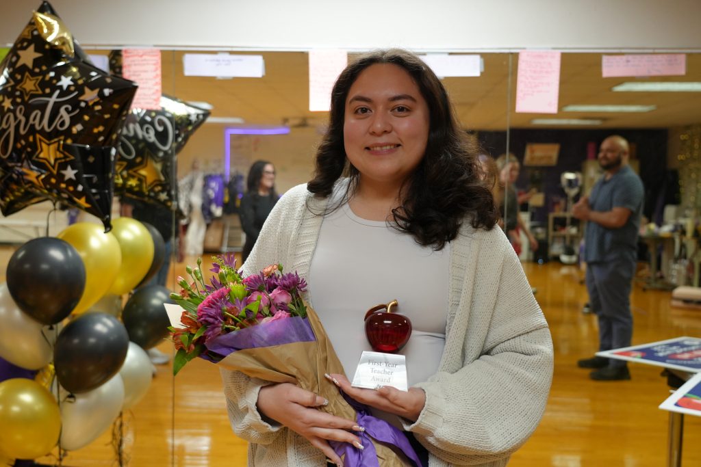Nataly Garza holding Red Apple New Teacher of the Year Poster