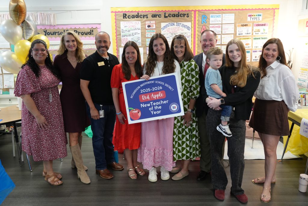 Elizabeth Richardson holding Red Apple poster surrounded by team