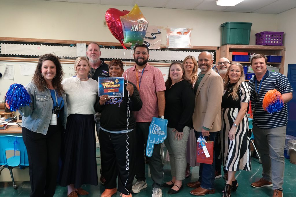 Super Teacher from Richardson West Junior High Fay Flanagan posing with students, district and campus admin holding certificate and balloons