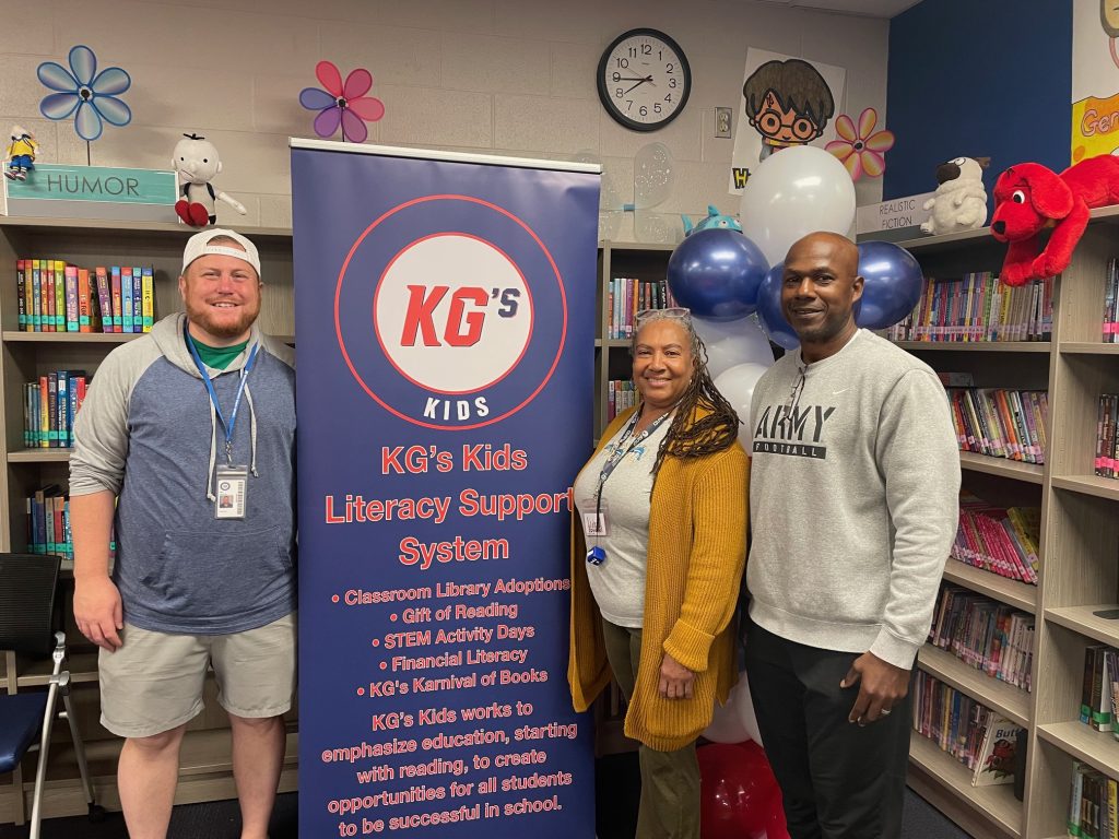 People standing around KGs Kids banner in library