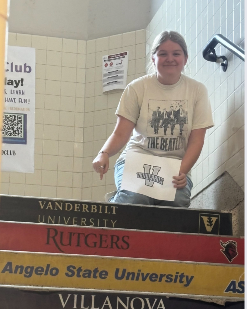 Chloe with Vanderbilt sign pointing to Vanderbilt stair step with logo.