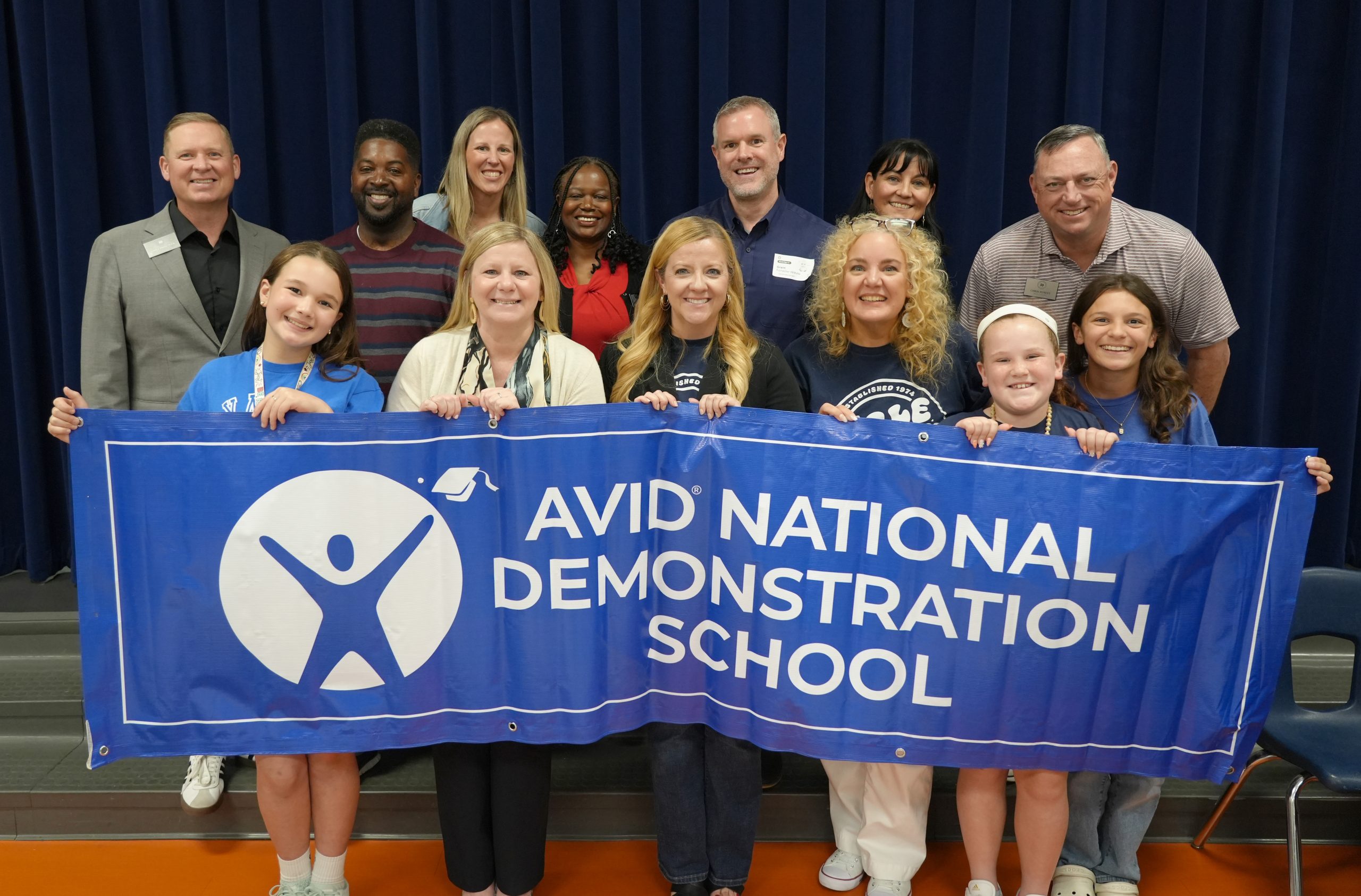 Adults and students holding large banner with AVID logo and AVID National Demonstration School text