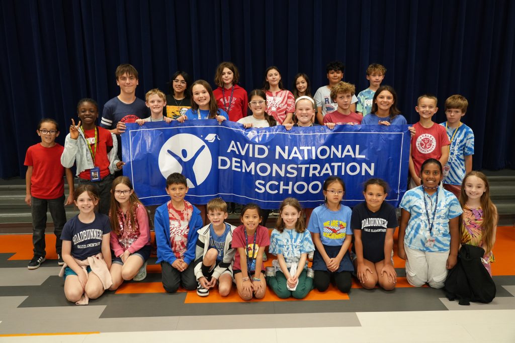 Students surrounding large banner with AVID logo and text AVID National Demonstration School