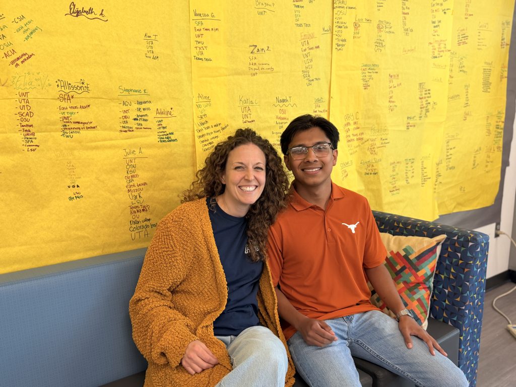 Jose with AVID teacher Alex Gandy sitting in front of college acceptances wall