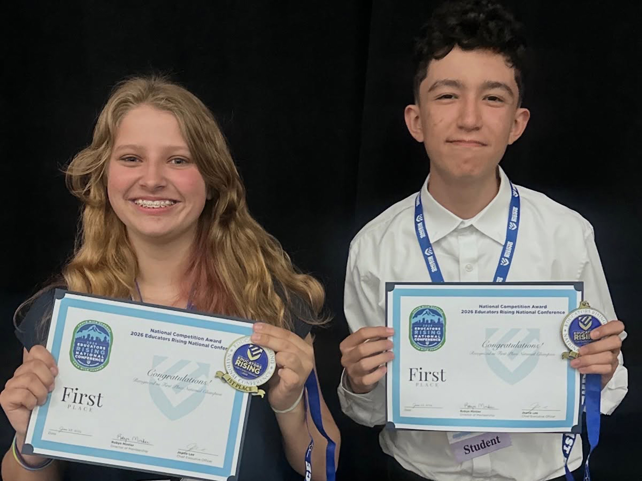Two students holding 1st place certificates