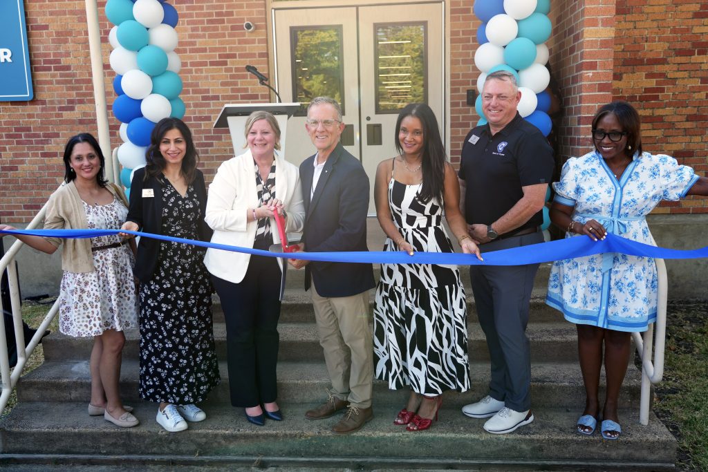 Superintendent, board members, and JA CEO cutting blue ribbon standing in front of balloons