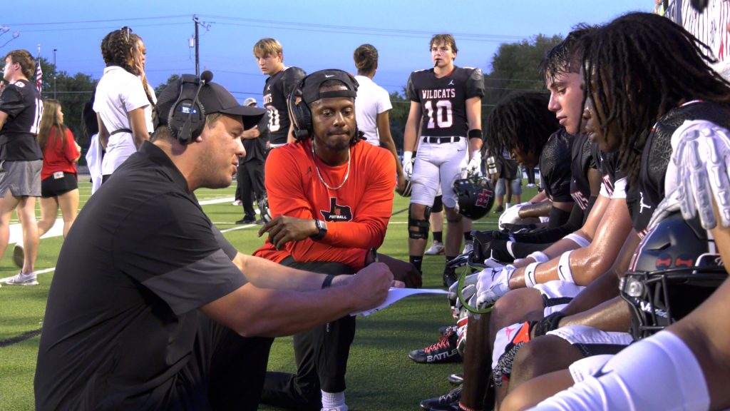 Football players speaking with coaches on the sidelines