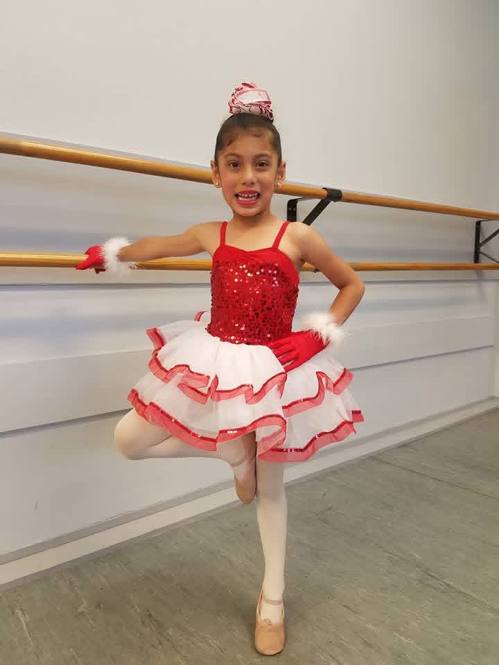 Brianna Mora as a young girl wearing red sequined ballet dress in dance studio